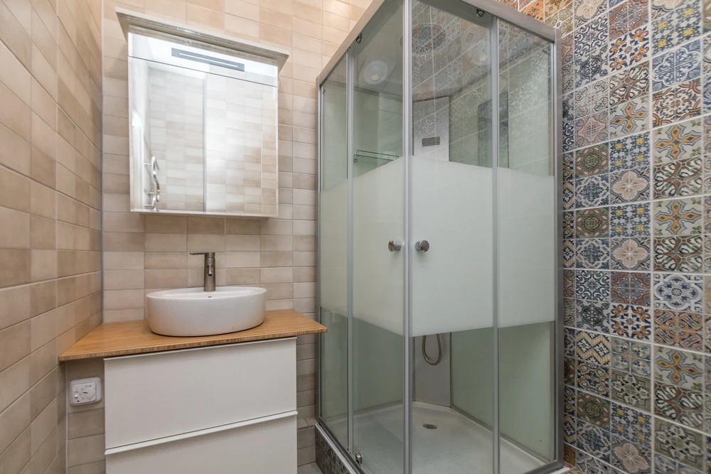 Salle de bain moderne compacte avec douche à l'italienne fermée par paroi vitrée coulissante