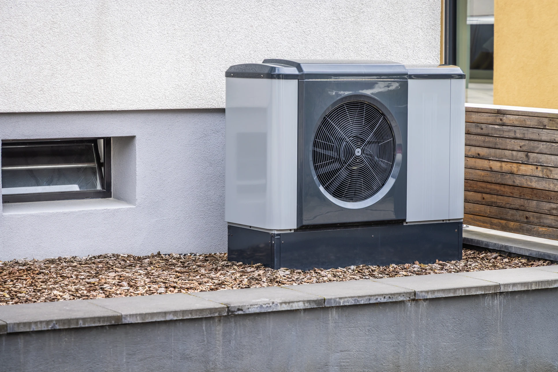 Extérieur résidentiel moderne avec pompe à chaleur air-eau installée sur terrasse pavée