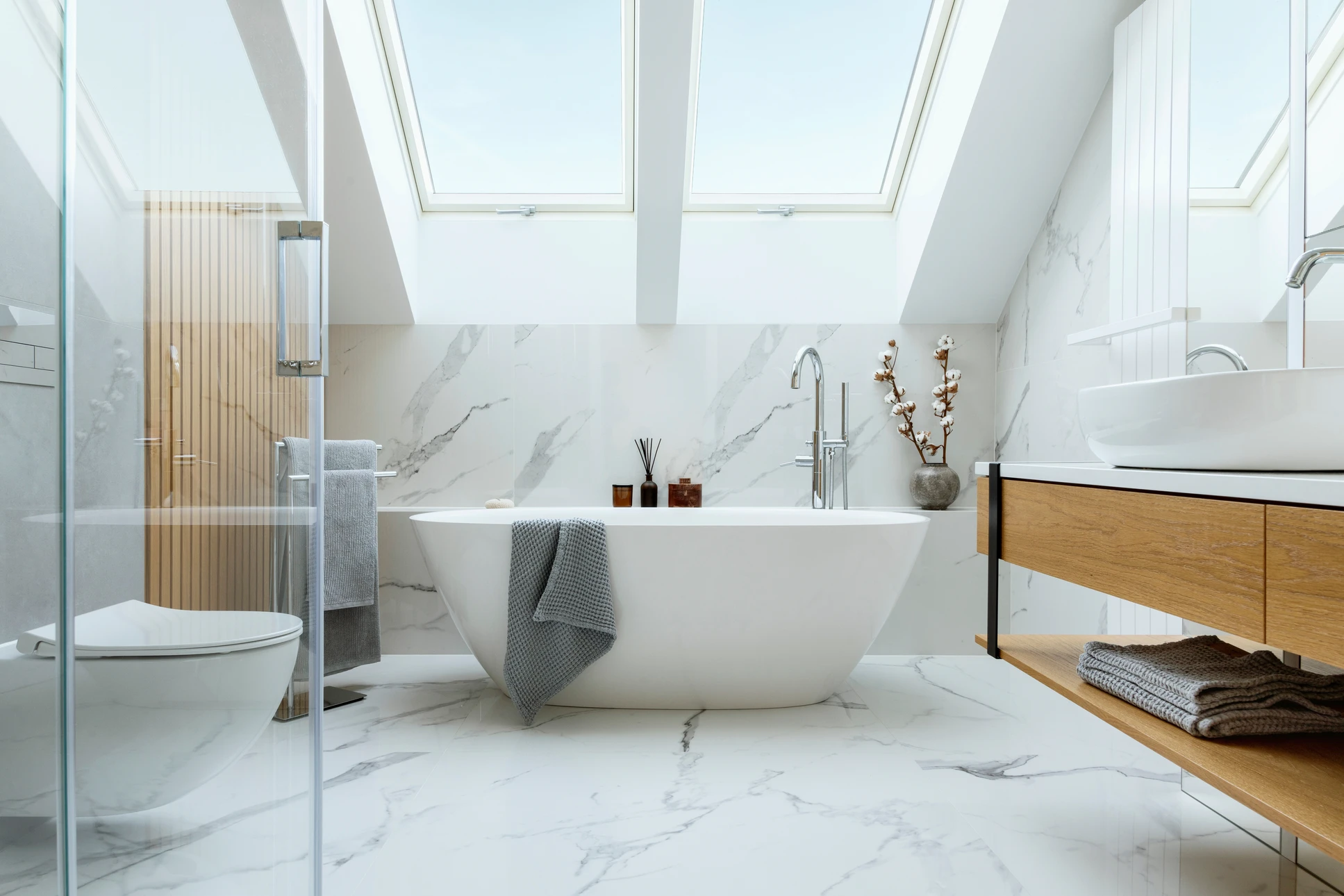 Plombier en salopette bleue réparant la plomberie sous un lavabo de salle de bain, allongé au sol avec des outils